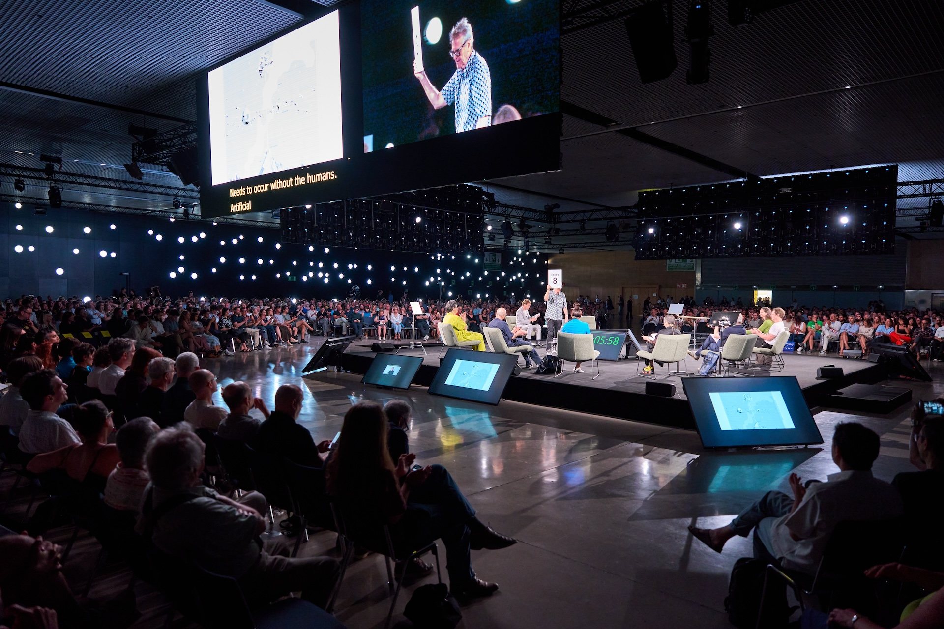 Opening plenary Becoming More-Than-Human at UIA Barcelona 2026, with panellists on a central stage surrounded by a seated audience and large screens above