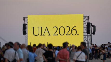 Crowd gathered at dusk in front of a large yellow LED screen reading UIA 2026 at the UIA World Congress of Architects Barcelona 2026