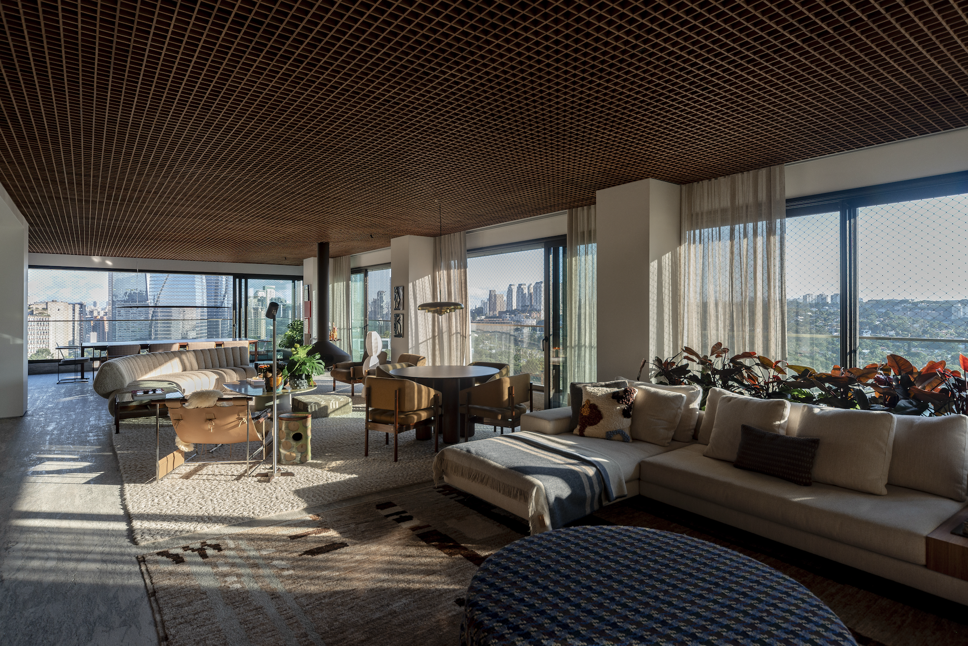Integrated living area at CRR | Arborea by Triplex Arquitetura, with modular sofa, dining table, suspended fireplace and continuous windows over São Paulo in Itaim Bibi